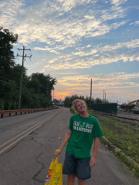 A volunteer carrying supplies down the road at sunset